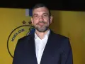 Michał Jurecki w garniturze na tle żółtej ściany z logo "Kielce".
