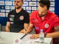 Krzysztof Łyżwa, zawodnik ARGED KPR Ostrovia, podpisuje dokumenty. Obok siedzi trener.
