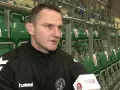 Marcin Pilch udziela wywiadu przed rzędem zielonych krzesełek na trybunach.