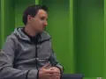 Artur Sadowski w szarej bluzie z kapturem siedzi na tle zielonych ścian, opowiadając o swoich pasjach.