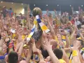 Tłum świętuje zwycięstwo, unosząc puchar. Kibice w żółto-niebieskich barwach, jak na meczach kielce liga mistrzów, cieszą się z sukcesu.