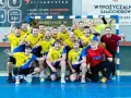Drużyna Unii Tarnów piłka ręczna świętuje zwycięstwo. Radośni zawodnicy w żółto-niebieskich strojach pozują do wspólnego zdjęcia.