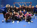 Drużyna piłki ręcznej KPR Bukowsko Dopiewo świętuje zwycięstwo. Radosne zawodniczki w strojach sportowych, z numerami na koszulkach, pozują do zdjęcia z trenerem.