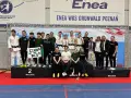Młodzi sportowcy świętują sukces na mistrzostwa polski juniorów. Drużyna z transparentem "Czarni do boju" pozuje na podium.