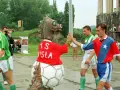 Artur Woźniak w barwach Wisły daje piątkę z maskotką. Piłkarze w zielonych strojach wychodzą na boisko.