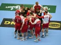 Drużyna piłkarzy ręcznych Polski w czerwonych strojach z białymi detalami, zjednoczona w kółku. To kluczowy moment przed meczem, być może decydującym o dalszych losach w mistrzostwach świata.