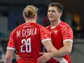 Dwóch zawodników w czerwonych koszulkach z orłem na piersi, jeden z nich z numerem 28, świętuje sukces w meczu polska słowacja piłka ręczna.