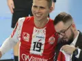 Uśmiechnięty Bartłomiej Tomczak w czerwonej koszulce z numerem 19, obok niego mężczyzna w garniturze.