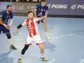 Kamil Adamski w akcji, rzuca piłkę do bramki. Zawodnik w białej koszulce z czerwonymi pasami i numerem 5.