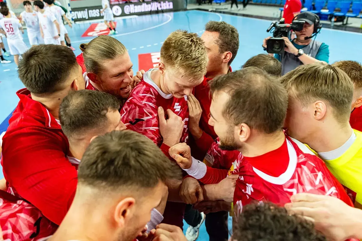 Piłkarze ręczni w czerwonych strojach świętują zwycięstwo. Emocje po meczu, a gdzieś w tle czeka mistrzostwa świata w piłce ręcznej terminarz.