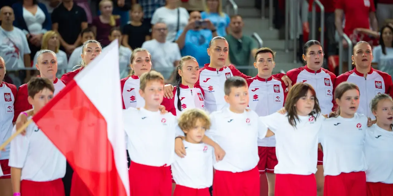 Młode zawodniczki i zawodnicy w strojach reprezentacji Polski, z biało-czerwoną flagą, przed meczem piłka ręczna kobiet mistrzostwa świata.