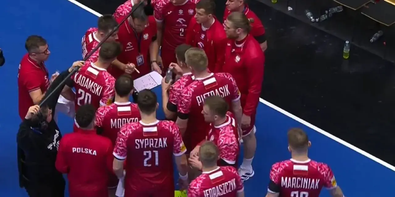 Drużyna piłki ręcznej Polska w czerwonych strojach z białymi detalami, podczas narady taktycznej przed meczem z Niemcami.