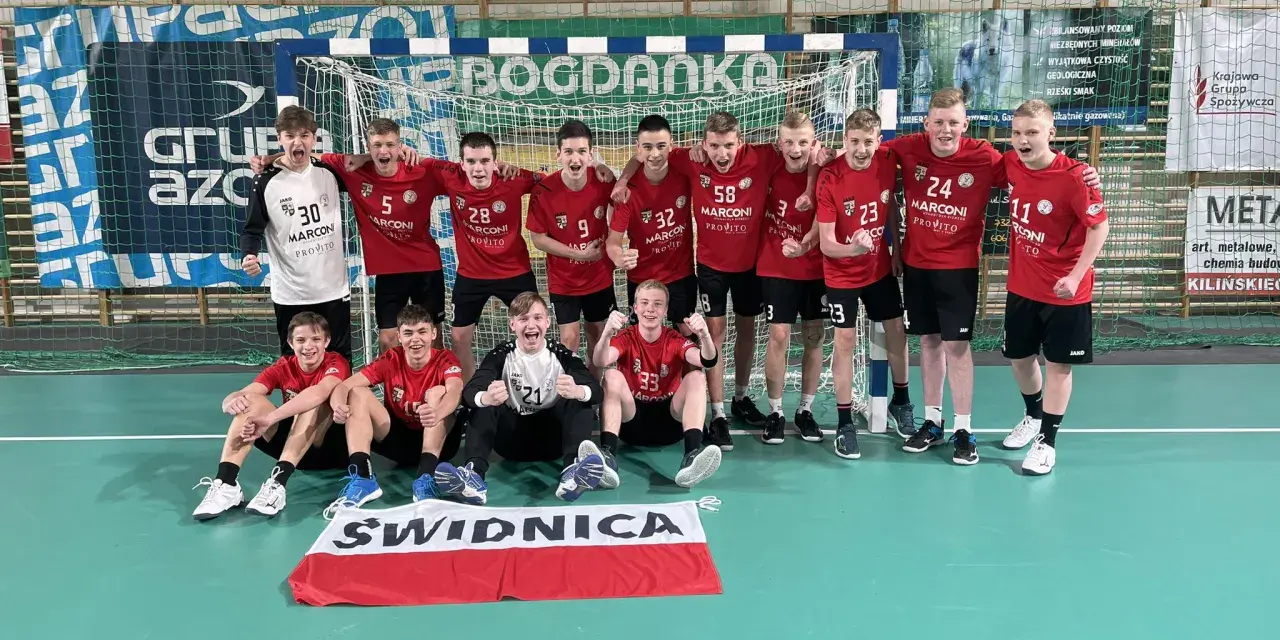 Drużyna piłki ręcznej z numerami na koszulkach, w tym Damian Borkowski, świętuje zwycięstwo.