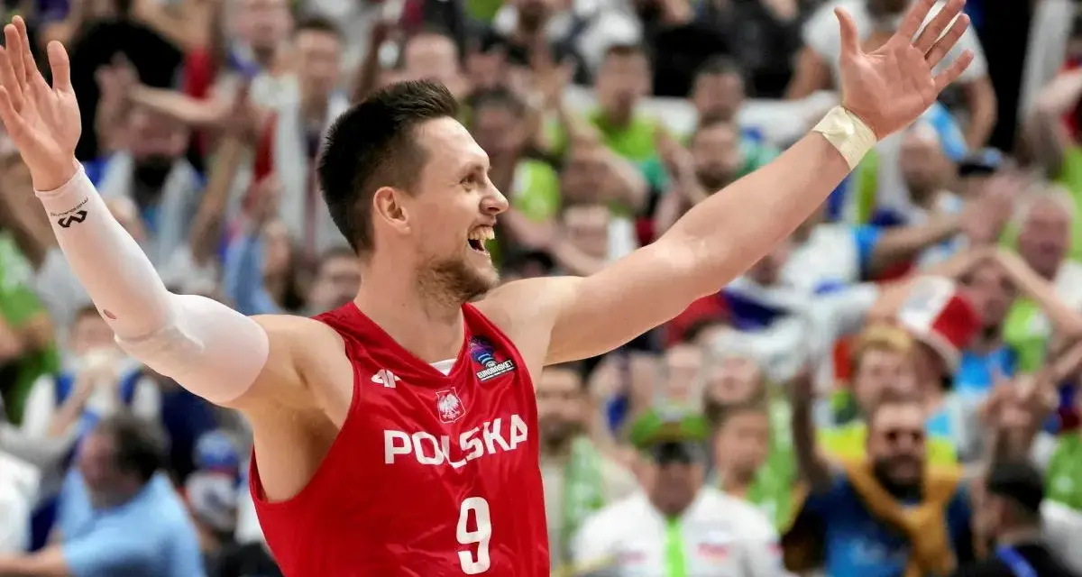 Bartosz Szczepanik w koszulce z numerem 9, z podniesionymi rękami, świętuje zwycięstwo na tle rozentuzjazmowanych kibiców.