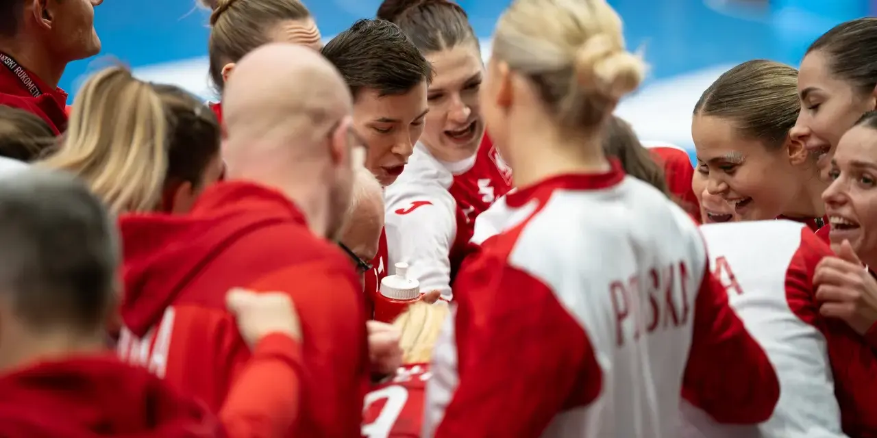 Drużyna piłki ręcznej w czerwonych strojach, zjednoczona przed meczem. Emocje i determinacja na twarzach zawodniczek podczas mistrzostw świata.