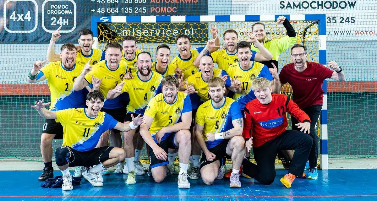 Drużyna Unii Tarnów piłka ręczna świętuje zwycięstwo. Radośni zawodnicy w żółto-niebieskich strojach pozują do wspólnego zdjęcia.