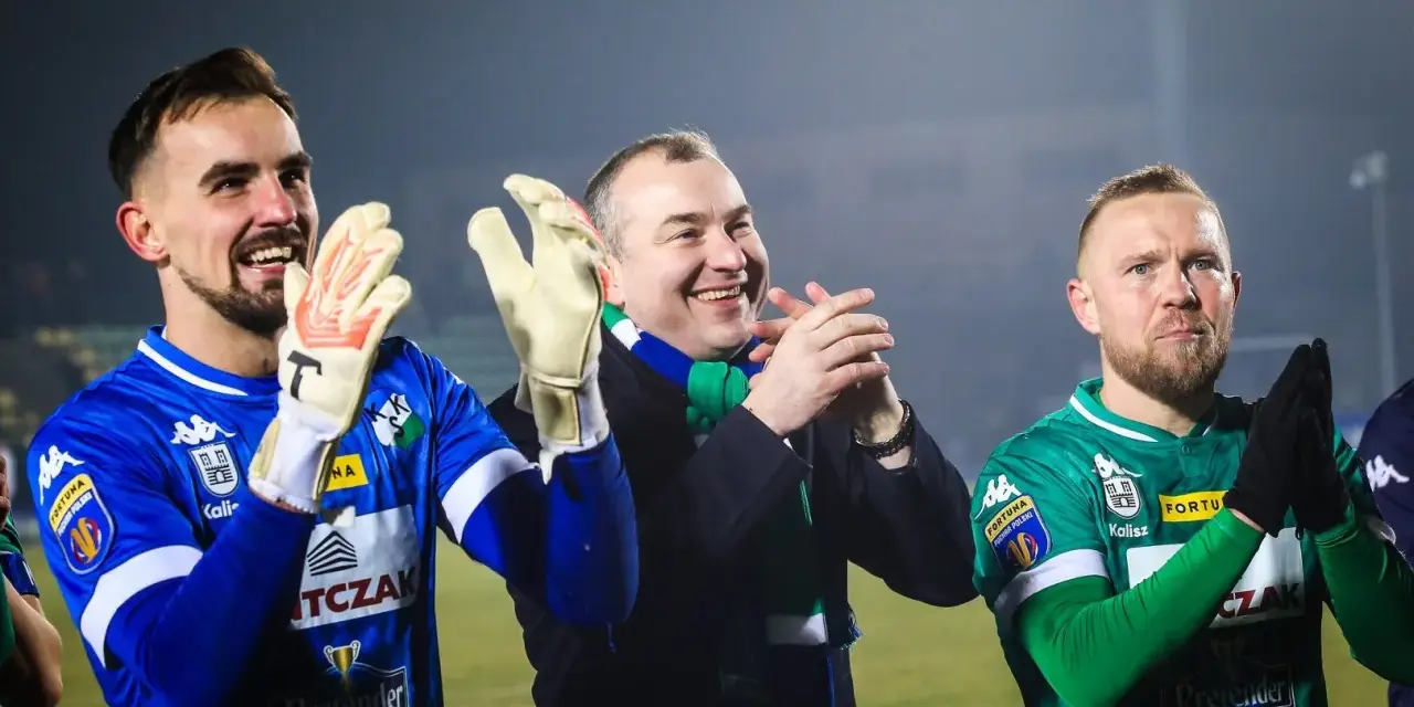 Piłkarze MKS Kalisz, bramkarz w niebieskiej koszulce i zawodnik w zielonej, klaszczą razem z kibicami.