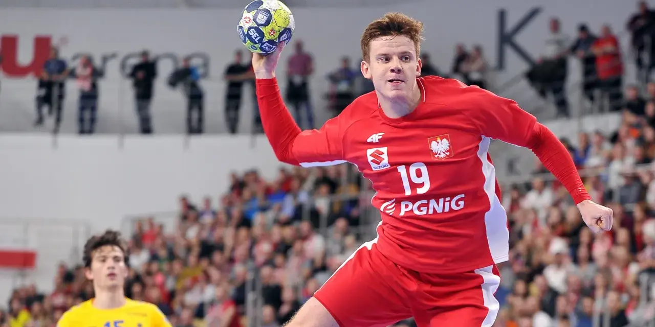 Jan Czuwara w akcji, rzuca piłką do bramki. Zawodnik w czerwonej koszulce z numerem 19.
