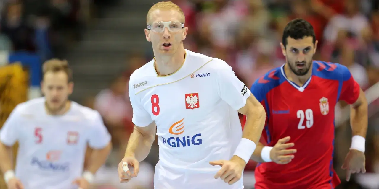 Kamil Bielecki w okularach ochronnych, z numerem 8 na koszulce, biegnie podczas meczu. Obok zawodnik z numerem 29.