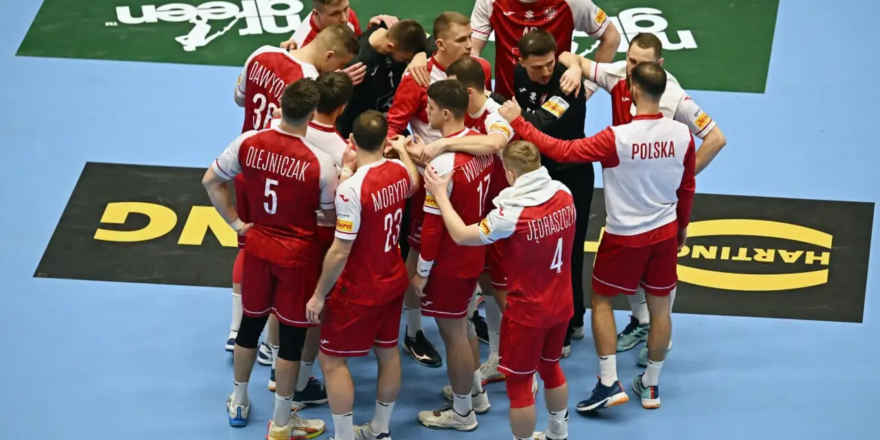 Drużyna piłkarzy ręcznych Polski w czerwonych strojach z białymi detalami, zjednoczona w kółku. To kluczowy moment przed meczem, być może decydującym o dalszych losach w mistrzostwach świata.