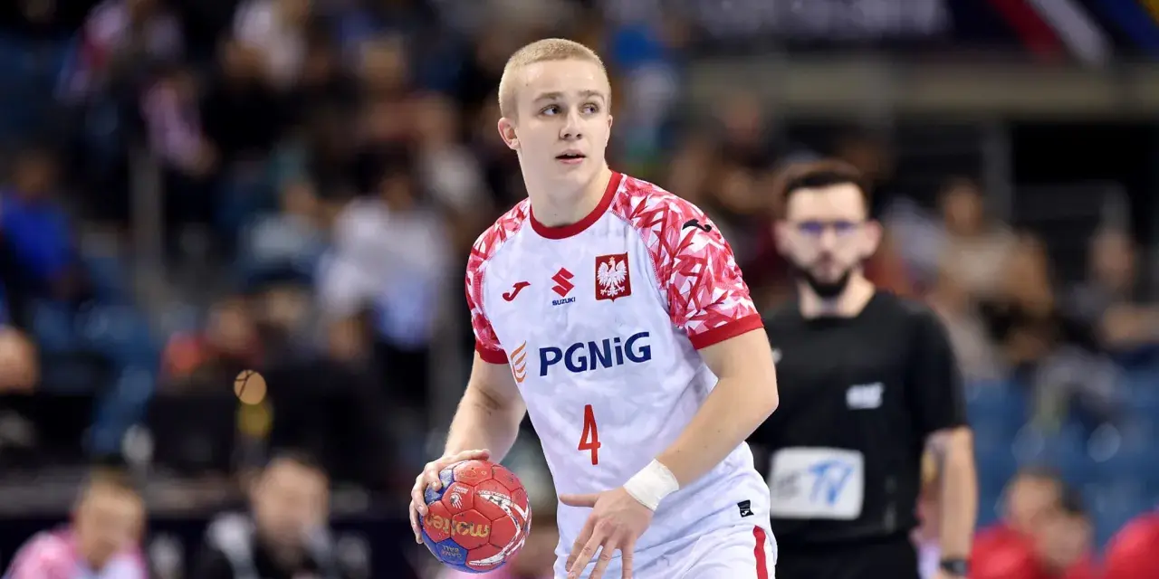 Młody zawodnik w białej koszulce z orłem i numerem 4, gotowy do rzutu piłką ręczną.