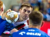 Piłkarz ręczny Luc Steins z piłką w ręku, otoczony przez obrońców.