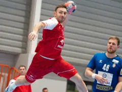 Piłkarz ręczny w skoku do rzutu, w czerwonej koszulce z logo ORLEN. Obok niego stoi zawodnik w niebieskiej koszulce z numerem 46. To reprezentacja Serbii w piłce ręcznej mężczyzn.