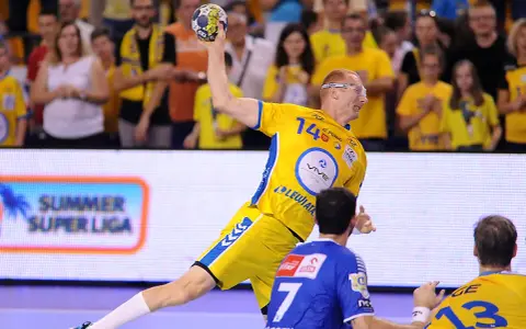 Piłkarz ręczny w żółtej koszulce z numerem 14 rzuca piłkę podczas eliminacji mistrzostw europy w piłce ręcznej grupa polska.