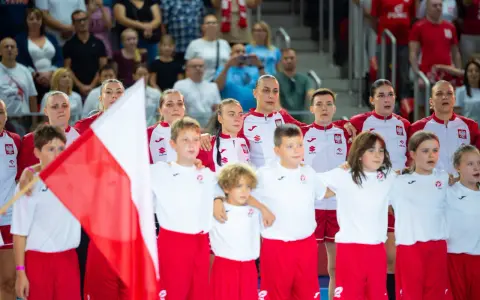 Młode zawodniczki i zawodnicy w strojach reprezentacji Polski, z biało-czerwoną flagą, przed meczem piłka ręczna kobiet mistrzostwa świata.