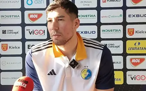 Daniel Dujshebaev w koszulce z herbem klubu, przed ścianką sponsorską z logo "Industria Kielce".