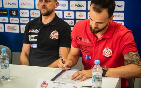 Krzysztof Łyżwa, zawodnik ARGED KPR Ostrovia, podpisuje dokumenty. Obok siedzi trener.