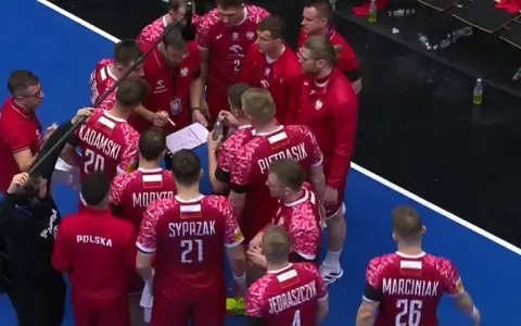Drużyna piłki ręcznej Polska w czerwonych strojach z białymi detalami, podczas narady taktycznej przed meczem z Niemcami.