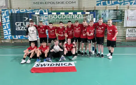 Drużyna piłki ręcznej z numerami na koszulkach, w tym Damian Borkowski, świętuje zwycięstwo.