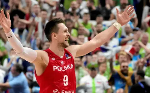 Bartosz Szczepanik w koszulce z numerem 9, z podniesionymi rękami, świętuje zwycięstwo na tle rozentuzjazmowanych kibiców.