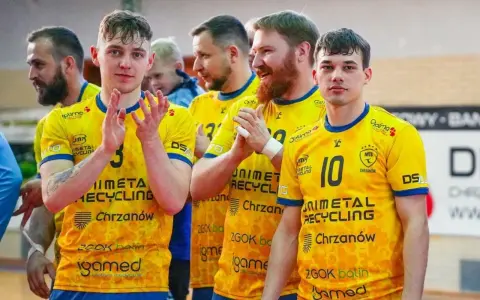 Drużyna MTS Chrzanów w żółtych koszulkach z numerami 3 i 10. Zawodnicy klaszczą, świętując zwycięstwo.