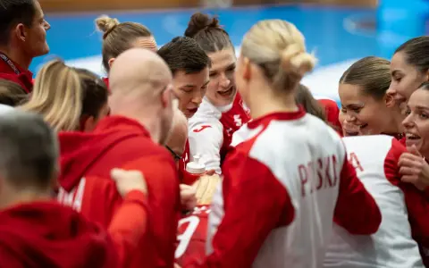 Drużyna piłki ręcznej w czerwonych strojach, zjednoczona przed meczem. Emocje i determinacja na twarzach zawodniczek podczas mistrzostw świata.