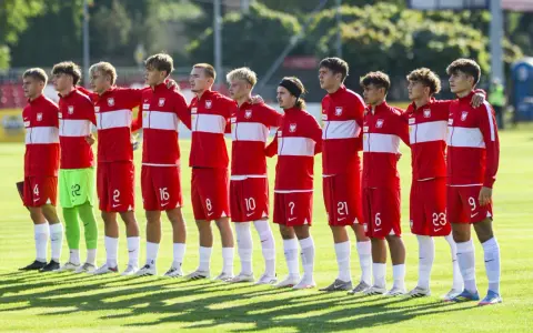 Drużyna Polski na Mistrzostwach Europy do lat 17. Piłkarze w czerwonych strojach z białymi pasami stoją w rzędzie, gotowi do meczu.