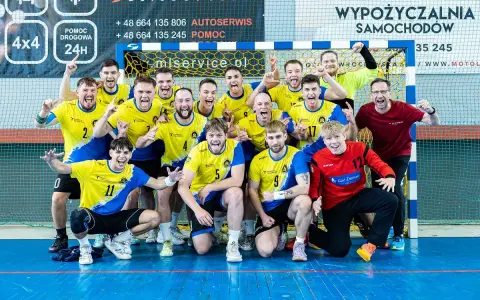 Drużyna Unii Tarnów piłka ręczna świętuje zwycięstwo. Radośni zawodnicy w żółto-niebieskich strojach pozują do wspólnego zdjęcia.