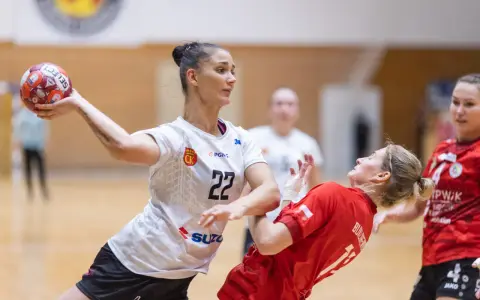 Piłkarka Suzuki Korona Handball Kielce rzuca piłkę. Rywalka w czerwonej koszulce próbuje ją zablokować.