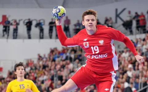Jan Czuwara w akcji, rzuca piłką do bramki. Zawodnik w czerwonej koszulce z numerem 19.