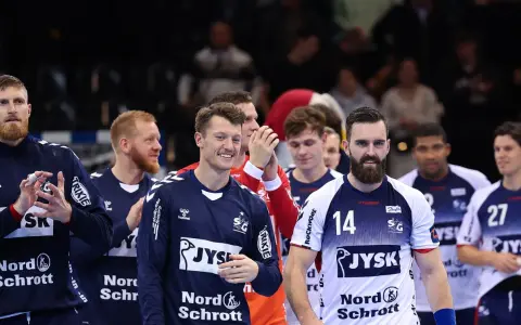 Emil Jakobsen z brodą i numerem 14 na koszulce, w otoczeniu drużyny piłkarzy ręcznych.