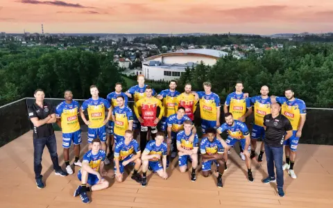 Drużyna piłkarzy ręcznych Vive Kielce pozuje do zdjęcia na tle panoramy miasta.