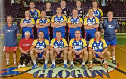 Drużyna SPR Chrobry Głogów pozuje do zdjęcia. Zawodnicy w żółto-niebieskich strojach sportowych, trenerzy i jedna kobieta.