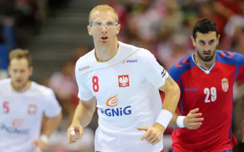 Kamil Bielecki w okularach ochronnych, z numerem 8 na koszulce, biegnie podczas meczu. Obok zawodnik z numerem 29.