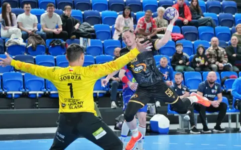 Bramkarz w żółtej koszulce broni rzut zawodnika w czarno-złotej koszulce z numerem 58. Kibice dopingują na trybunach, wśród nich widać logo KS Azoty Puławy.
