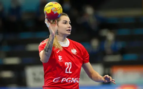 Aleksandra Rosiak w akcji, rzuca piłkę ręczną. Zawodniczka w czerwonej koszulce z numerem 22.
