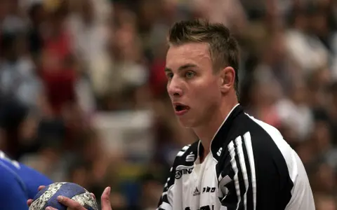 Filip Jicha, szczypiornista, z piłką w dłoni, skupiony na grze.