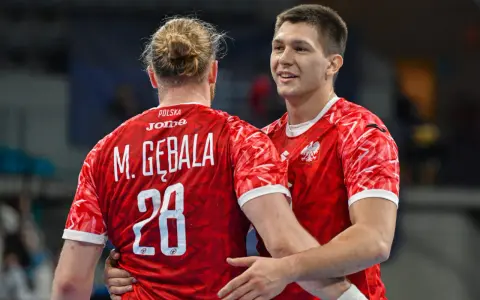 Dwóch zawodników w czerwonych koszulkach z orłem na piersi, jeden z nich z numerem 28, świętuje sukces w meczu polska słowacja piłka ręczna.