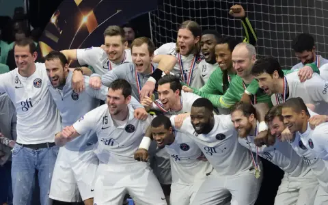 Drużyna PSG Handball świętuje zwycięstwo, otoczona kibicami.
