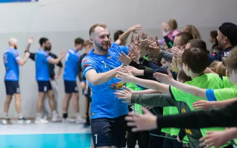 Gracz MKS Wieluń w niebieskiej koszulce z numerem 1 daje "piątki" młodym kibicom.